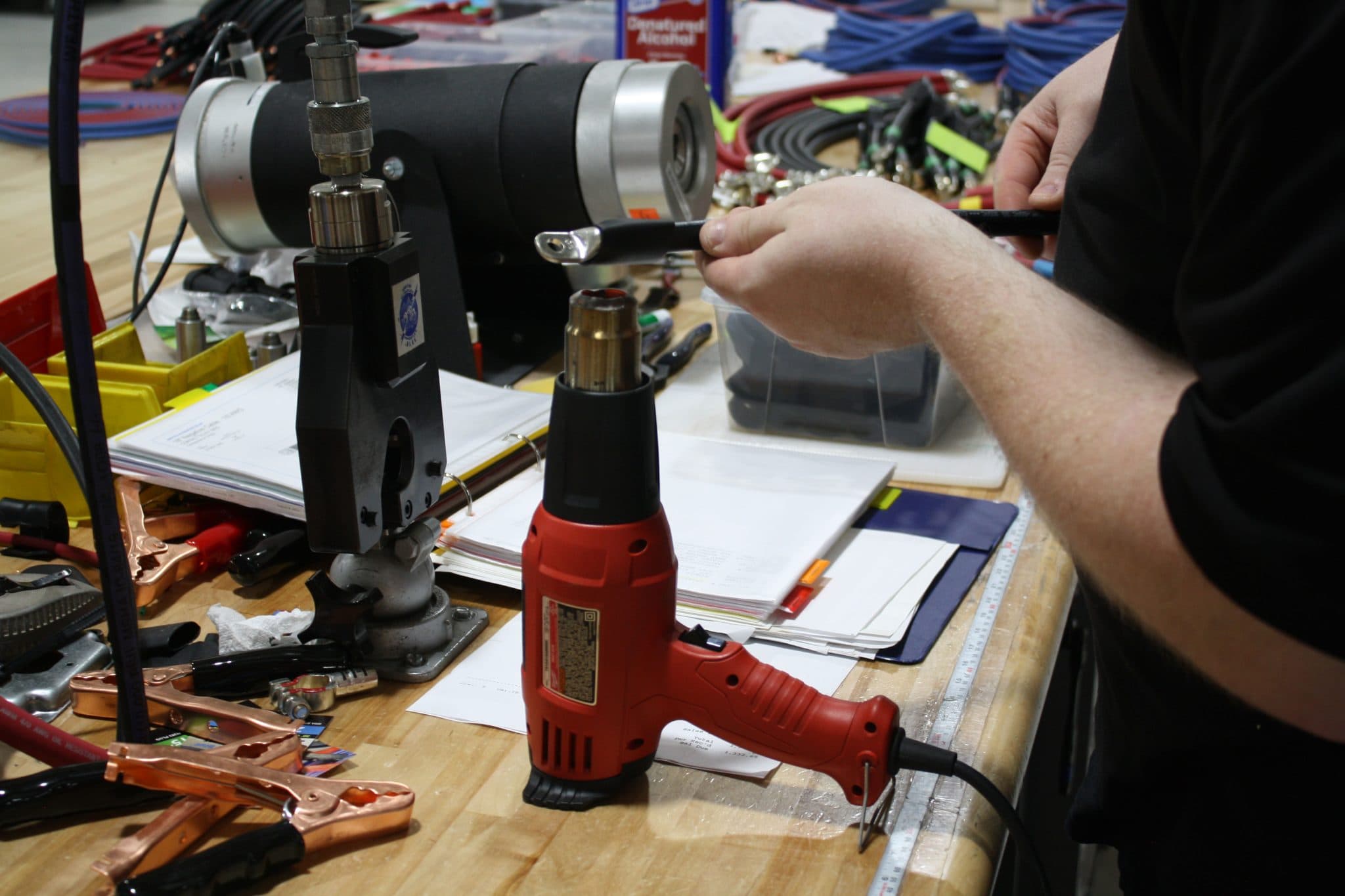 A technician crimping a lug onto heavy cable at an assembly bench