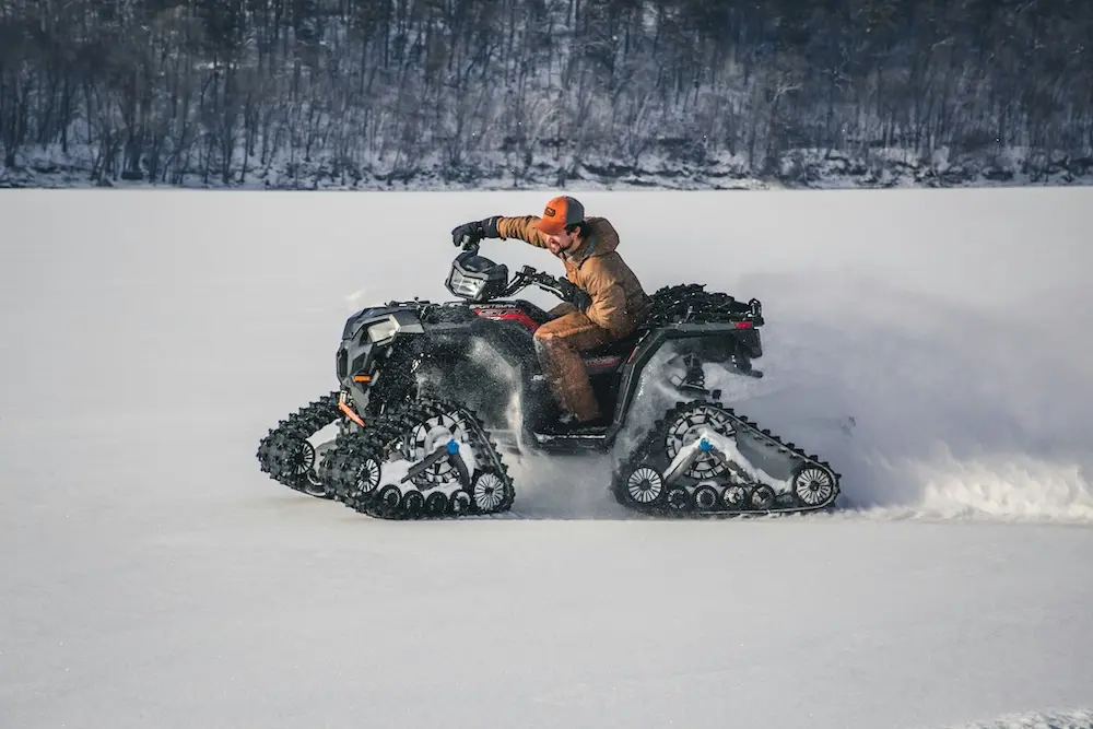 A tracked ATV running across deep snow
