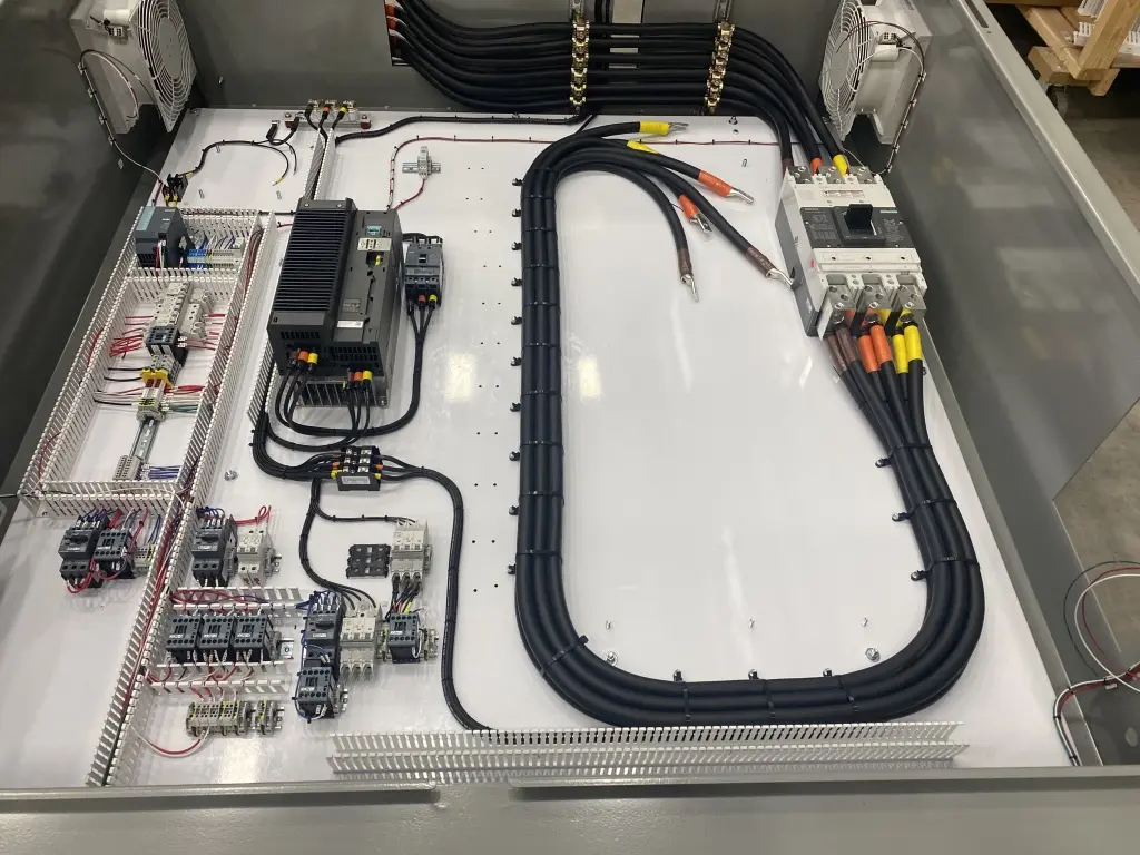 Heavy black conductors landed on a breaker inside an industrial control cabinet