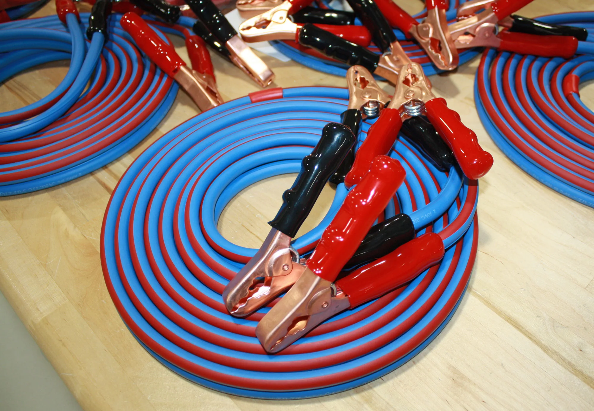 Coiled blue and red jumper cables with clamps attached, part-built on the bench